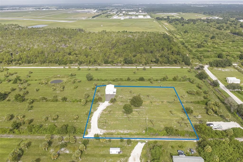 An aerial view shows a white building on a large, grassy lot with trees — 7023 AUSTRIAN BOULEVARD, PUNTA GORDA, FL