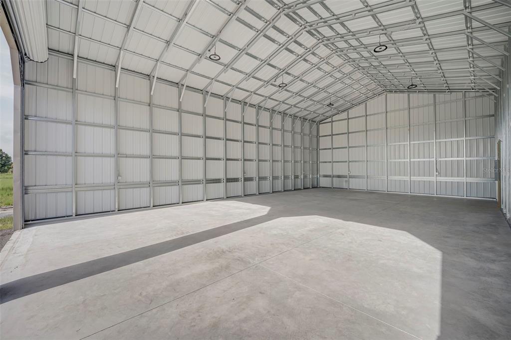 A spacious, empty metal warehouse building features a concrete floor and exposed steel framing — 7023 AUSTRIAN BOULEVARD, PUNTA GORDA, FL
