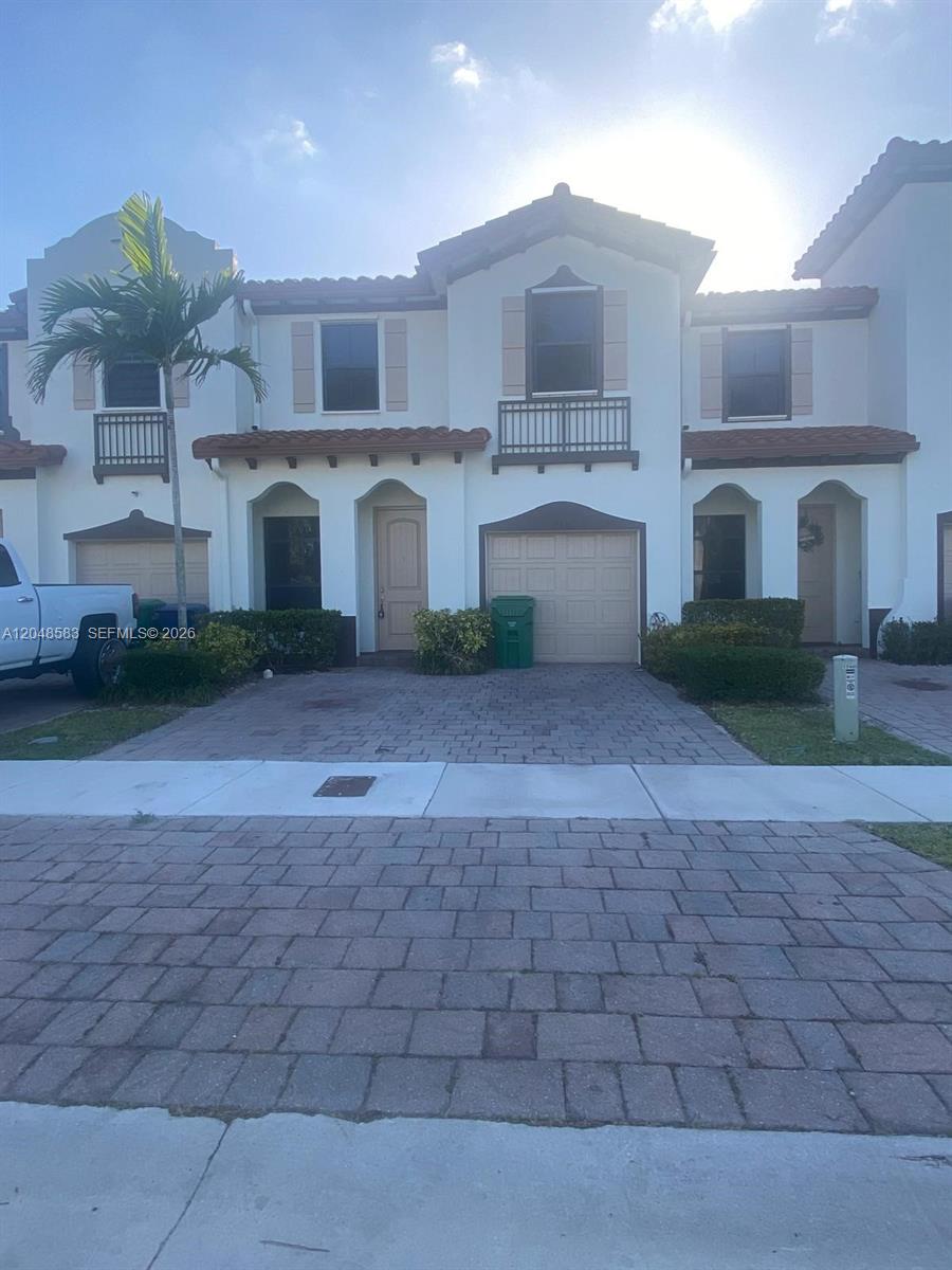 A two-story townhouse features a beige stucco exterior, a single-car garage, and a paved driveway — MIAMI, FL