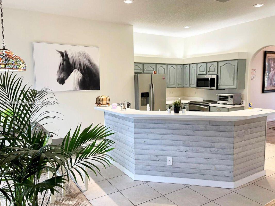A kitchen features light gray cabinets, a white countertop, and a wood-paneled breakfast bar — 12245 NE 56th Ave, Okeechobee FL 34972, OKEECHOBEE, FL
