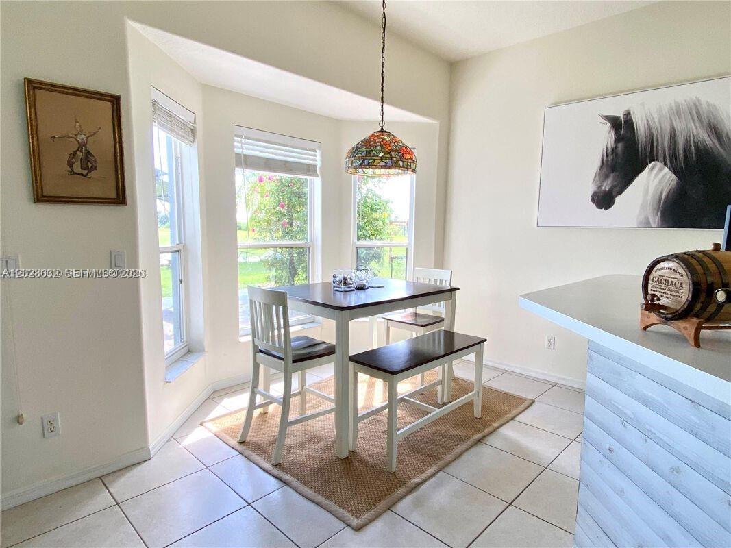 A dining area features a table with chairs and a bench under a stained-glass pendant — 12245 NE 56th Ave, Okeechobee FL 34972, OKEECHOBEE, FL
