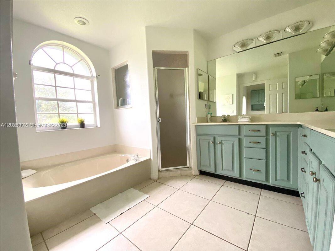 A bathroom features a soaking tub, a glass-enclosed shower, and light blue vanity cabinets — 12245 NE 56th Ave, Okeechobee FL 34972, OKEECHOBEE, FL
