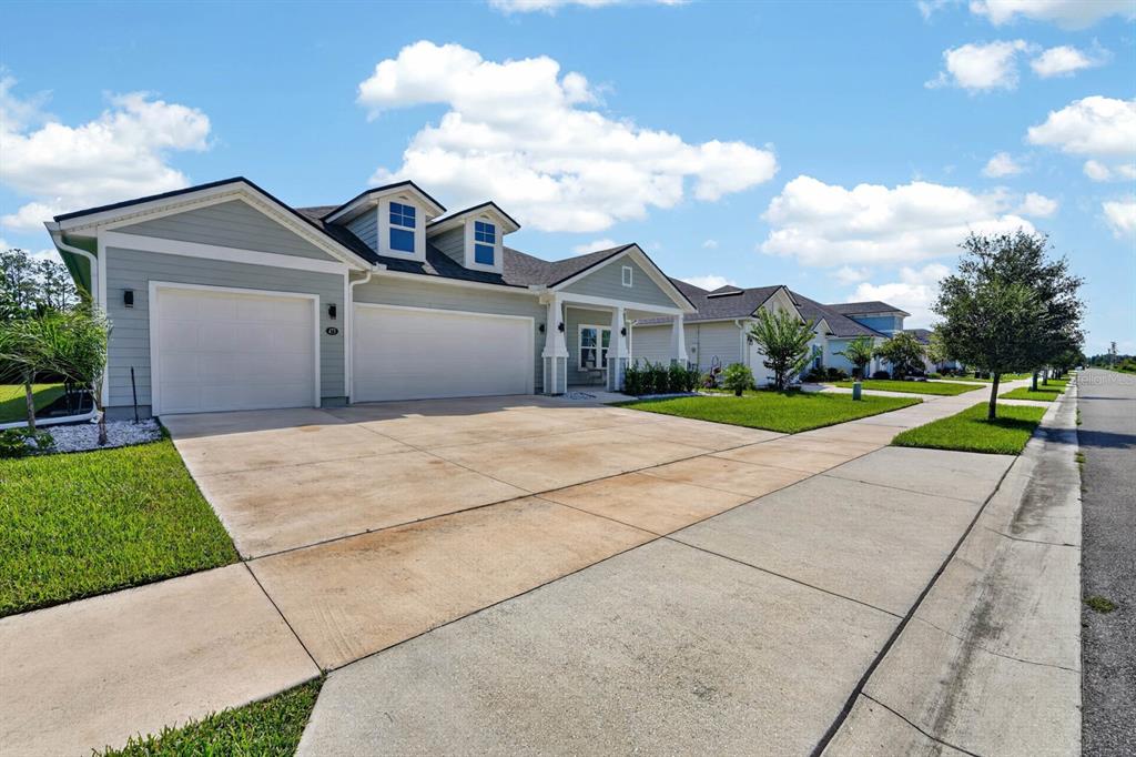 A light blue single-story house with a three-car garage and a front porch — 473 GRAND LANDINGS PARKWAY, PALM COAST, FL