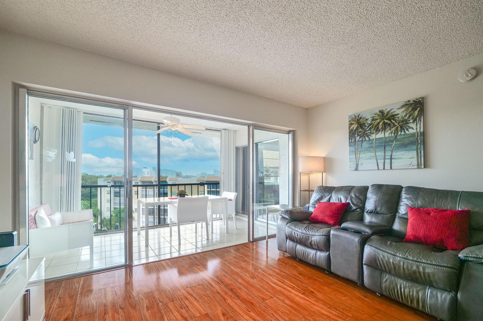 A living room with wood floors and a leather sofa opens onto a balcony — 3930 Inverrary Boulevard # d, Lauderhill FL 33319, LAUDERHILL, FL