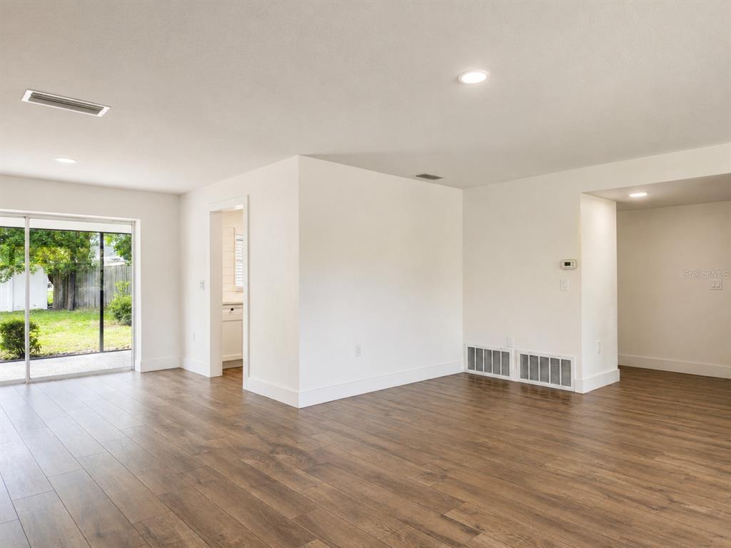 An interior view of a room with wood-look flooring, white walls, and a sliding glass door — 810 ALLAMANDA DRIVE, LARGO, FL