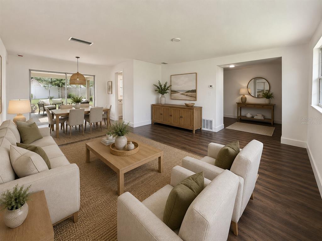 A living and dining room with wood-look flooring, neutral furniture, and a sliding glass door — 810 ALLAMANDA DRIVE, LARGO, FL