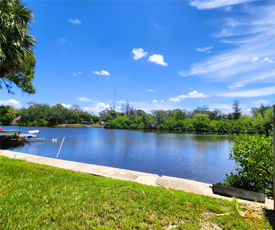 A view of a calm canal with a small boat docked near a grassy lawn — 6977 EDGEWATER DRIVE, NEW PORT RICHEY, FL