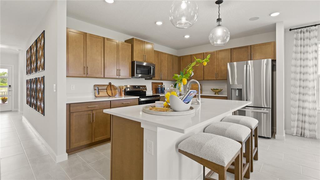 A modern kitchen features light wood cabinets, white countertops, a central island, and stainless appliances — 2261 CROWN ROCK BLUFF DRIVE, LAKE HAMILTON, FL
