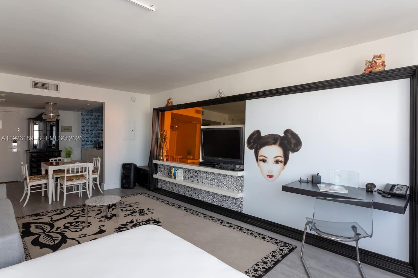 A living room features a large wall mirror, a television, and a built-in desk area — 1100 West Ave # 1004, Miami Beach FL 33139, MIAMI BEACH, FL