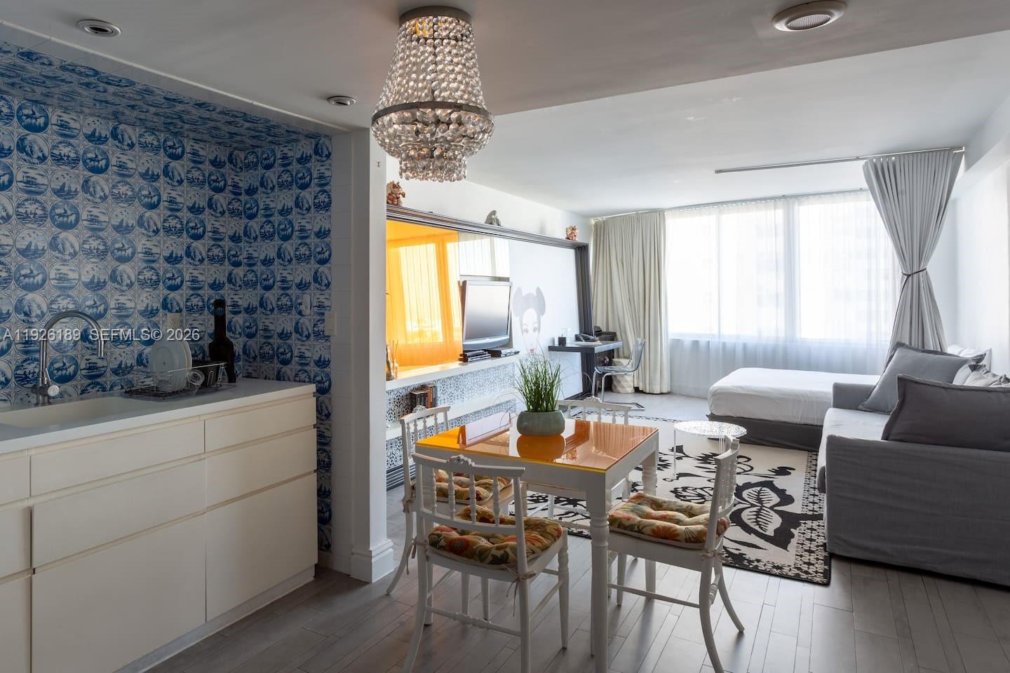 A studio apartment features a kitchen with blue patterned wallpaper, a dining area, and living space — 1100 West Ave # 1004, Miami Beach FL 33139, MIAMI BEACH, FL