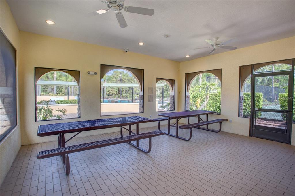 A covered outdoor patio features tiled flooring, two metal picnic tables, and arched windows — 3894 SAFFLOWER TERRACE, OVIEDO, FL