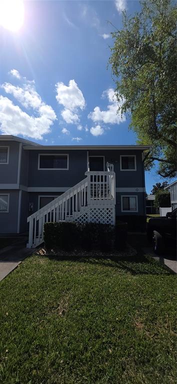 Exterior view of two-story apartment buildings with white staircases, blue siding, and green lawns — 6033 34TH STREET W UNIT 136, BRADENTON, FL