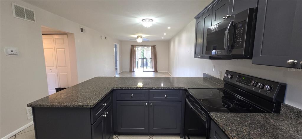 An empty room with light-colored tile flooring, a ceiling fan, and a sliding glass door — 6033 34TH STREET W UNIT 136, BRADENTON, FL