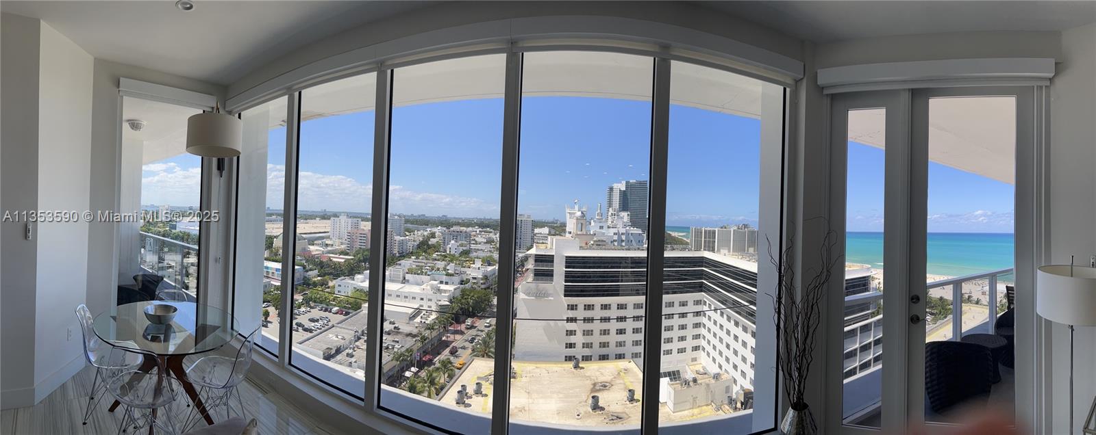 A dining area with a glass table and chairs overlooks a city and ocean view — 100 Lincoln Rd, Miami Beach FL 33139, MIAMI BEACH, FL