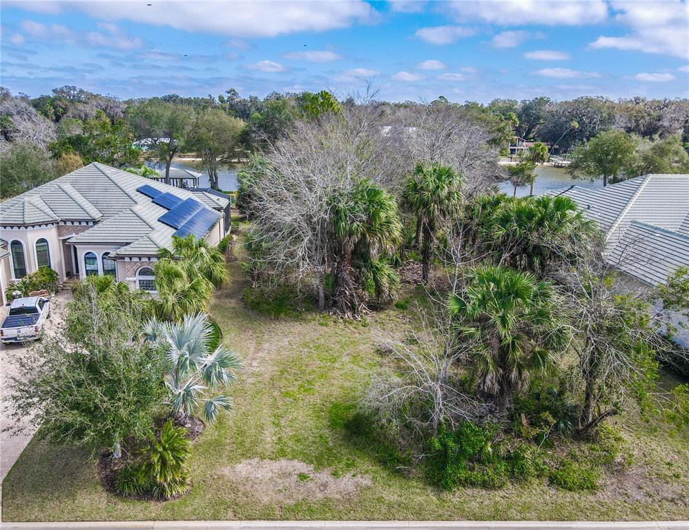 An aerial view shows a vacant residential lot situated between two houses near a lake — 121 LONGVIEW WAY N, PALM COAST, FL
