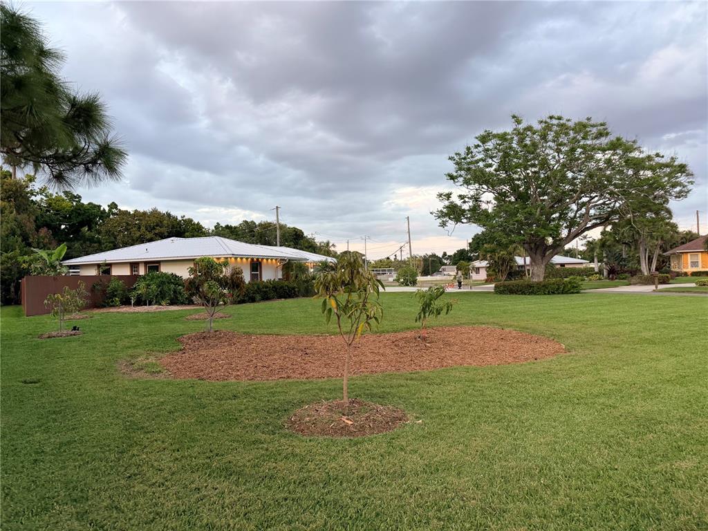 A grassy yard features several young trees in mulch beds in front of a house — 4620 7TH AVENUE W, BRADENTON, FL