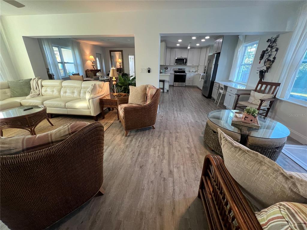 An open-concept living room and kitchen feature light wood-look flooring and wicker furniture — 4620 7TH AVENUE W, BRADENTON, FL