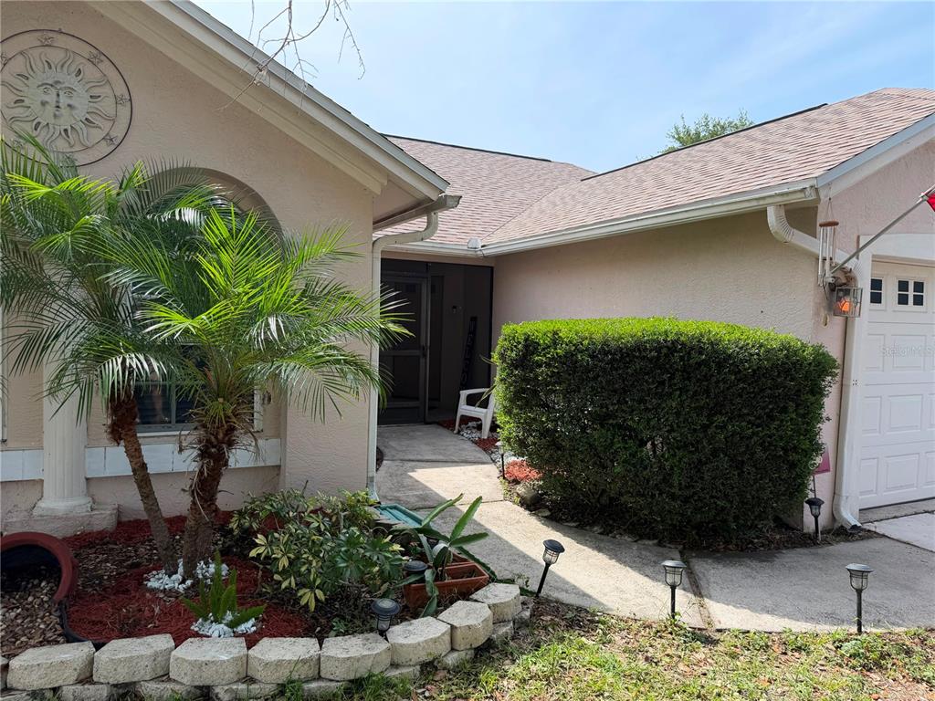 The exterior of a house features a palm tree, a large hedge, and a walkway — 908 45TH STREET E, BRADENTON, FL