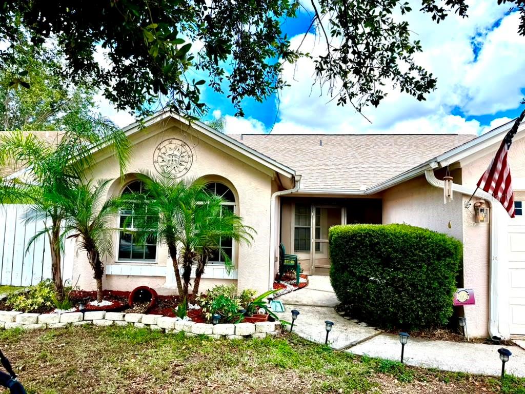 A single-story house with a beige stucco exterior, arched windows, palm trees, and a walkway — 908 45TH STREET E, BRADENTON, FL