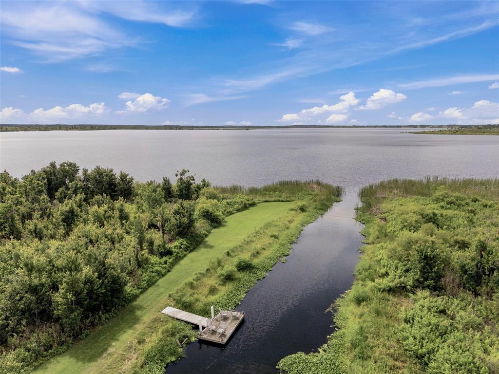 An aerial view shows a wooden dock extending into a narrow canal leading to a lake — 3210 GREAT HERON LOOP, POLK CITY, FL