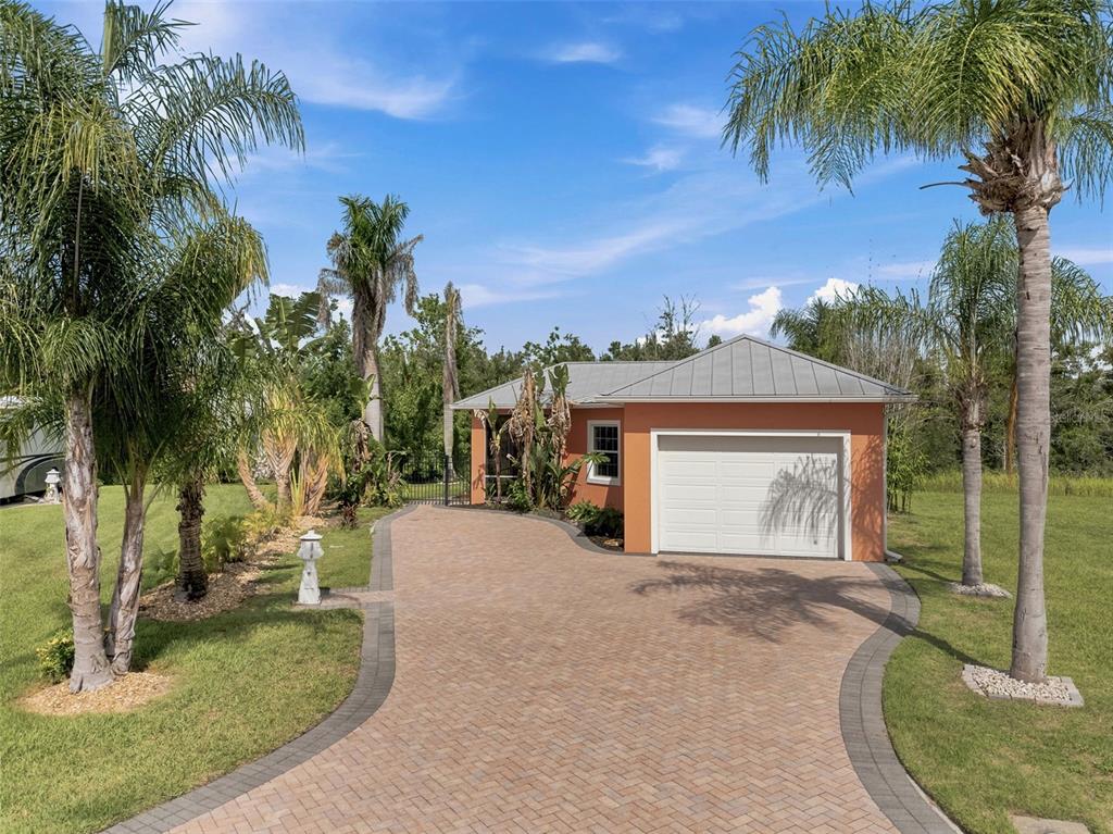 A peach-colored detached garage with a metal roof sits at the end of a paver driveway — 3210 GREAT HERON LOOP, POLK CITY, FL