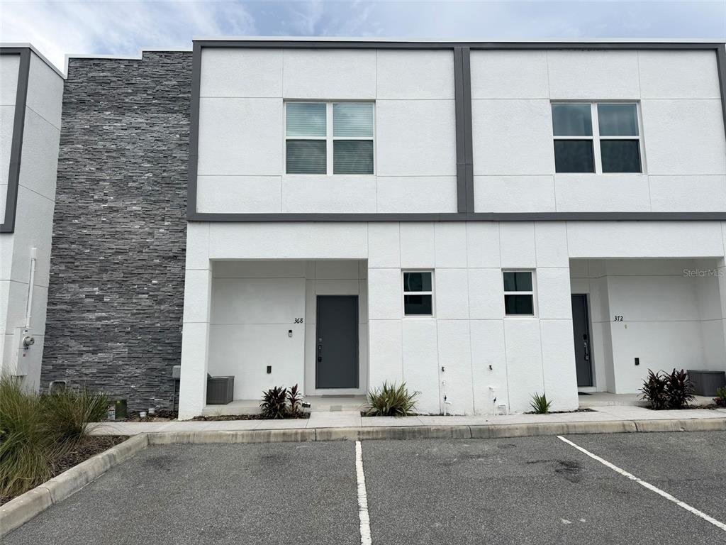 A modern two-story townhouse exterior features white stucco walls, dark trim, and gray stone accents — 368 FAMAGUSTA DRIVE, DAVENPORT, FL