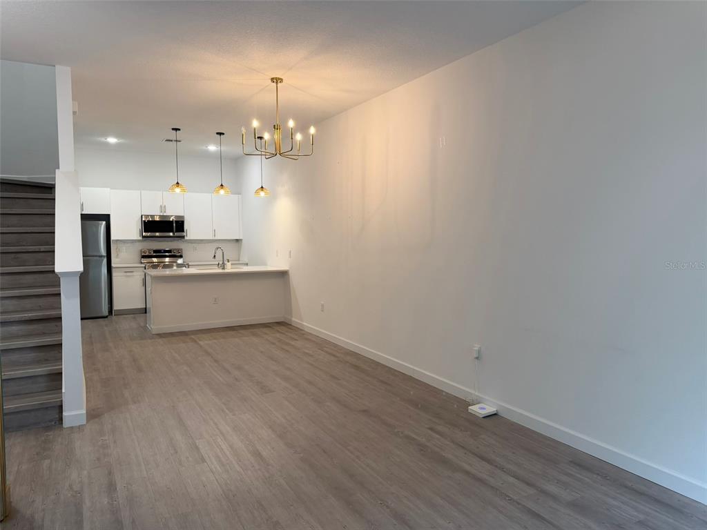 An open-concept kitchen with white cabinets and a dining area featuring a chandelier — 368 FAMAGUSTA DRIVE, DAVENPORT, FL