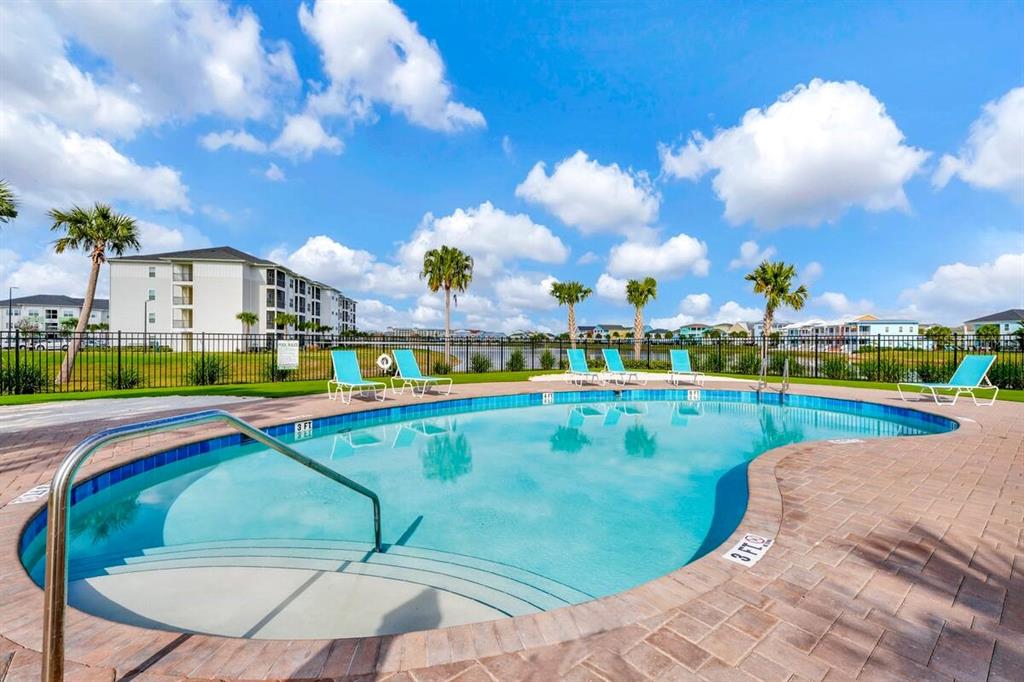 A swimming pool with lounge chairs sits in front of a multi-story apartment building — 2998 SALTED RIM ROAD, KISSIMMEE, FL