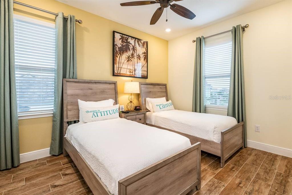 A bedroom features two twin beds with wooden frames, light yellow walls, and tile flooring — 2998 SALTED RIM ROAD, KISSIMMEE, FL
