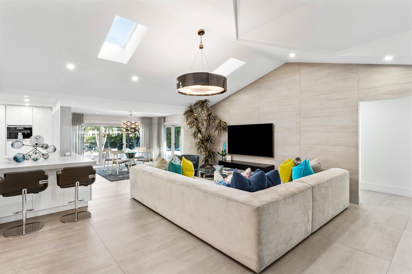 A white front door opens into a bright living room with a large sectional sofa — 820 N Atlantic Drive, Lantana FL 33462, LANTANA, FL