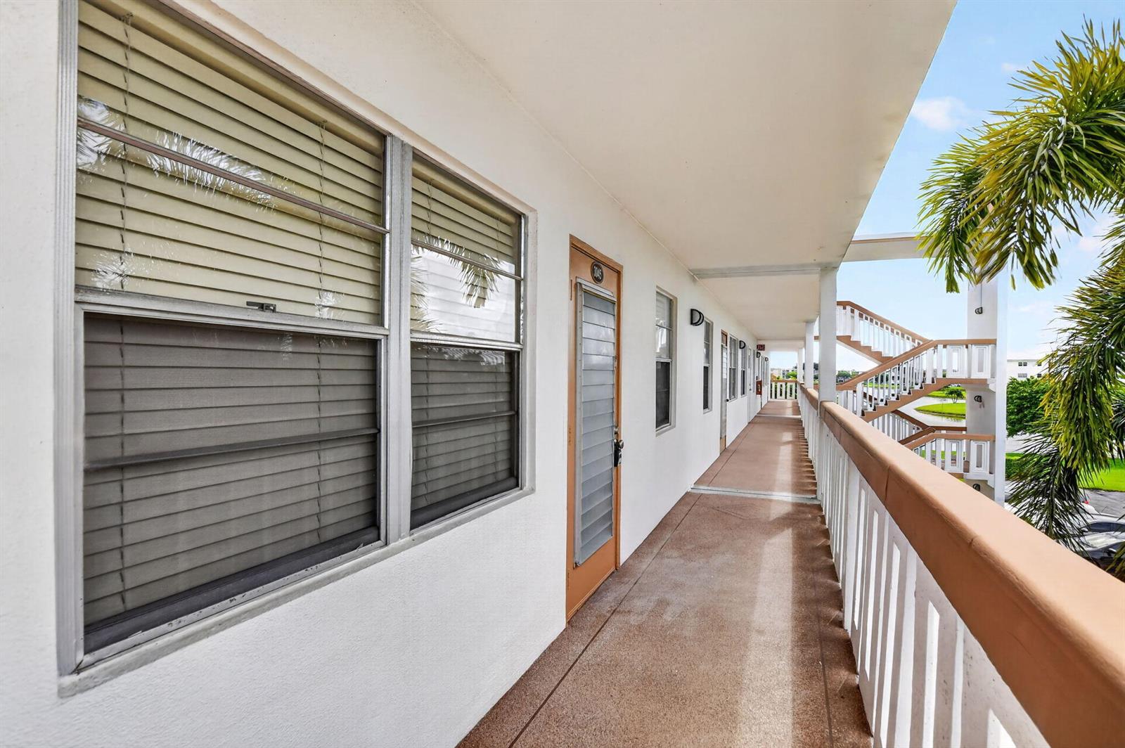 An exterior walkway with a brown railing leads past apartment doors and windows — 3045 Cornwall C, Boca Raton FL 33434, BOCA RATON, FL