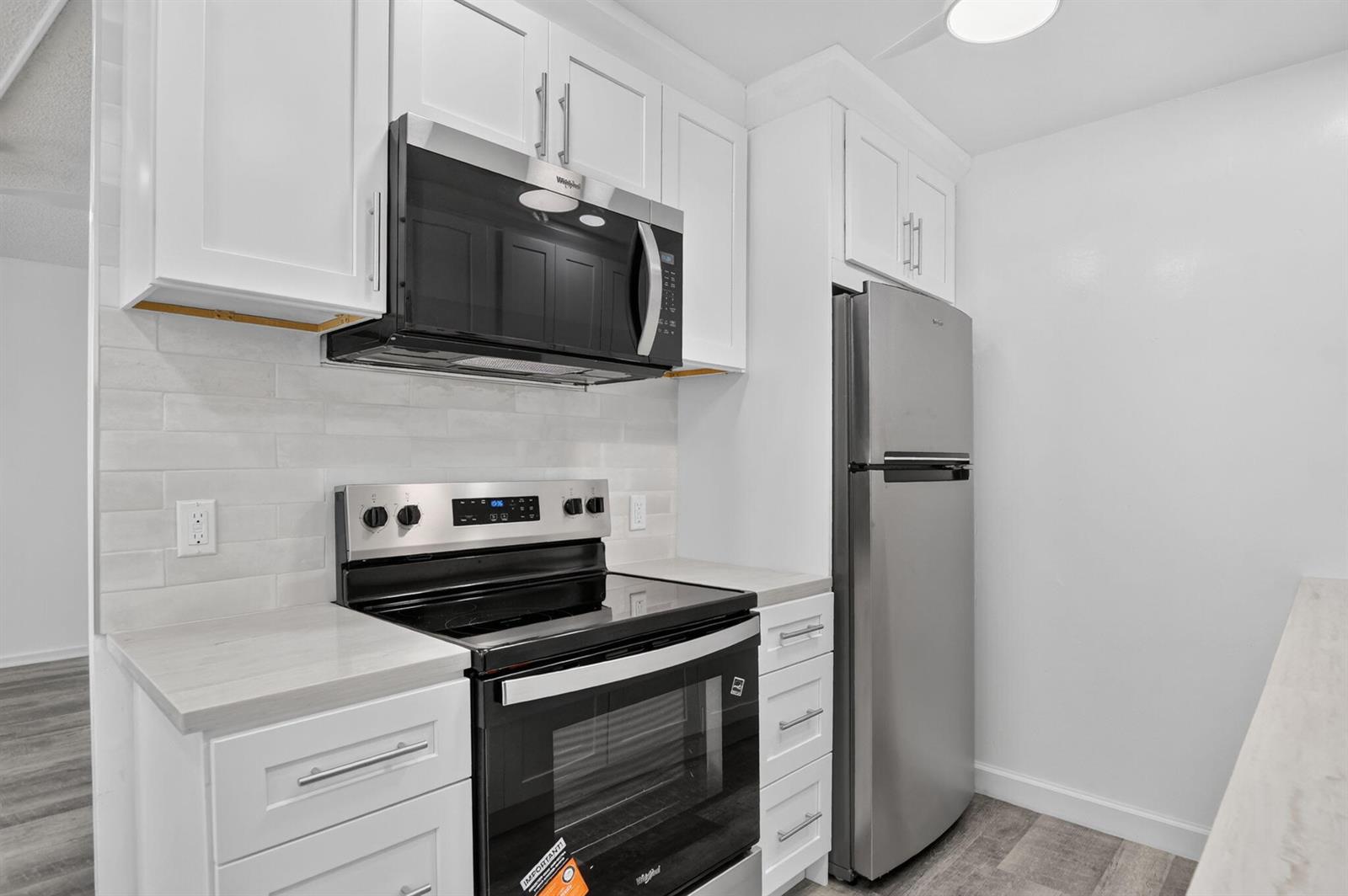 A kitchen features white cabinets, stainless steel appliances, and light-colored countertops — 3045 Cornwall C, Boca Raton FL 33434, BOCA RATON, FL