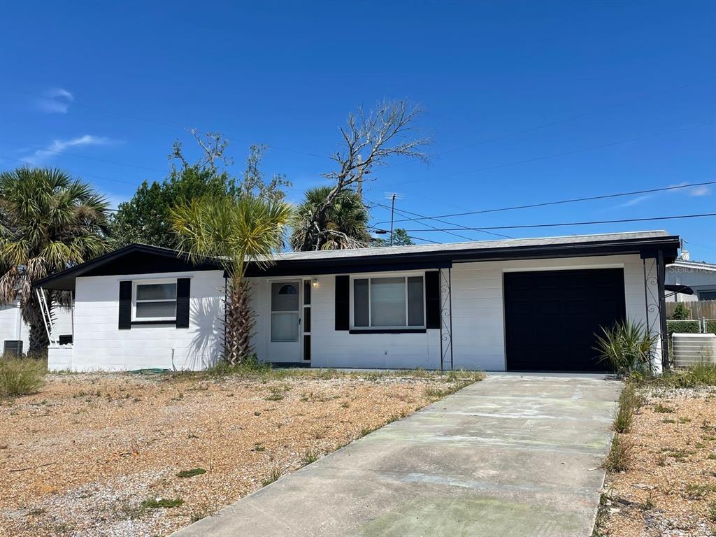 A single-story house with white exterior walls, black trim, and a front-facing garage — 1130 POWERSONG STREET, HOLIDAY, FL