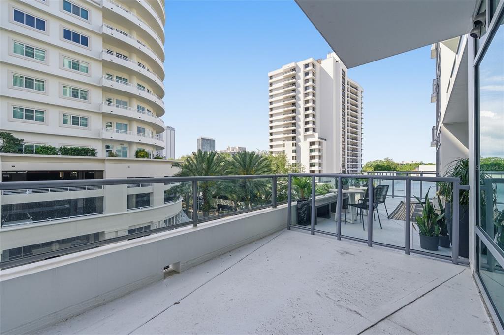 A balcony with a glass railing overlooks a city street and neighboring high-rise buildings — 101 S EOLA DRIVE UNIT 519, ORLANDO, FL