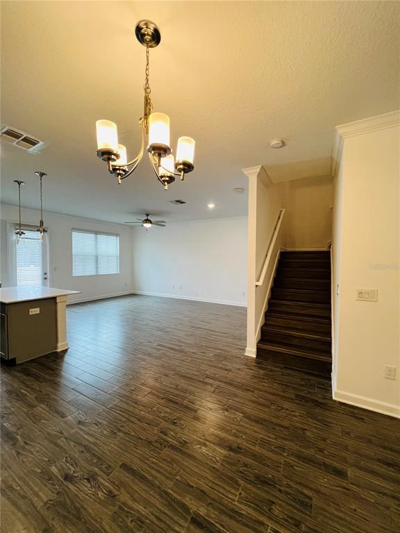 An open-concept living area features wood-look tile flooring, a chandelier, and a staircase — 11258 WHISTLING PINE WAY, ORLANDO, FL