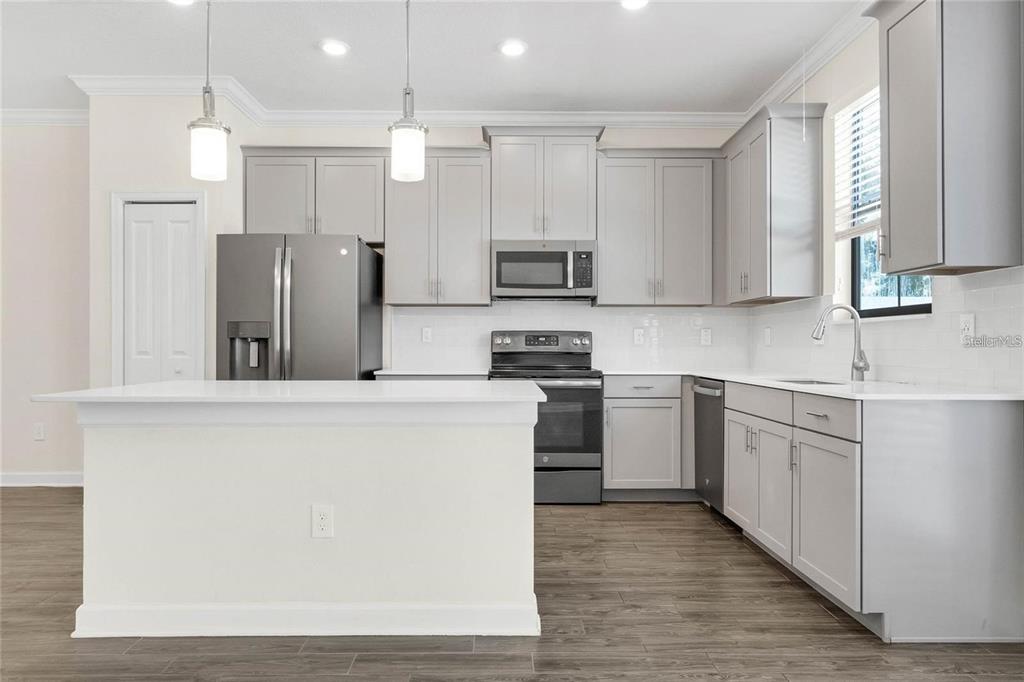 A kitchen features light gray cabinets, stainless steel appliances, white countertops, and a center island — 11258 WHISTLING PINE WAY, ORLANDO, FL
