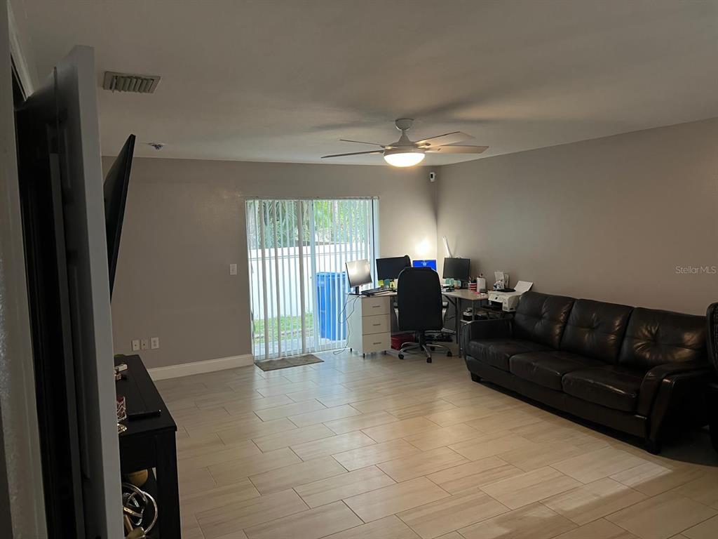 A living room features light tile flooring, a ceiling fan, a leather sofa, and a desk — 8423 EDGEWATER PLACE BOULEVARD, TAMPA, FL