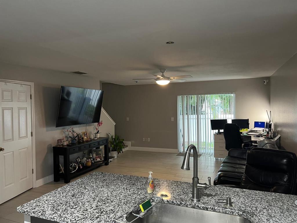 A kitchen island with a granite countertop overlooks a living area with a wall-mounted television — 8423 EDGEWATER PLACE BOULEVARD, TAMPA, FL