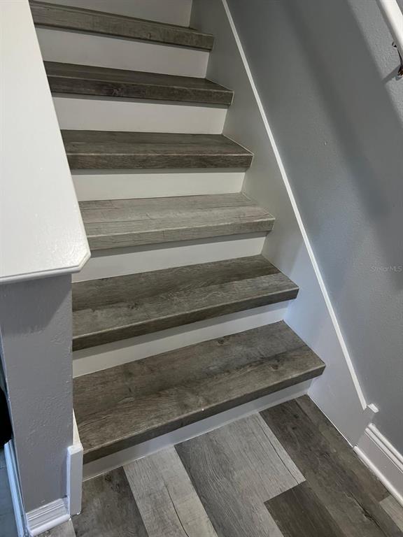 A staircase with wood-look treads and white risers leads upward between two walls — 8423 EDGEWATER PLACE BOULEVARD, TAMPA, FL