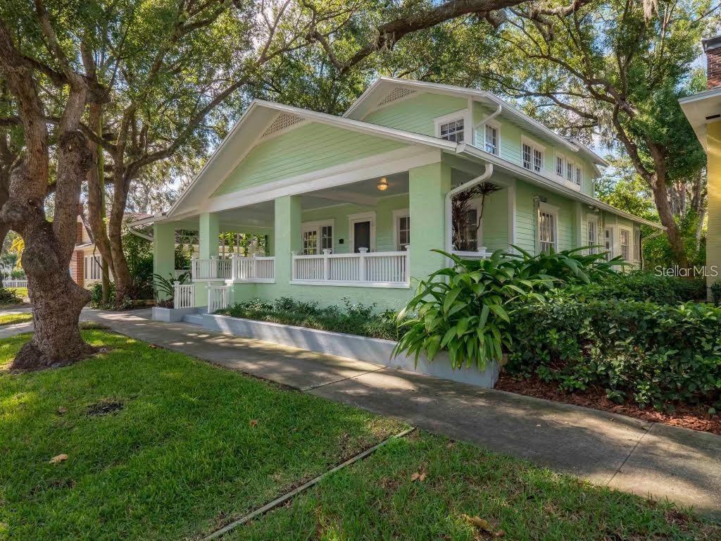 A light green bungalow with a large front porch sits under mature oak trees — 510 N SUMMERLIN AVENUE, ORLANDO, FL