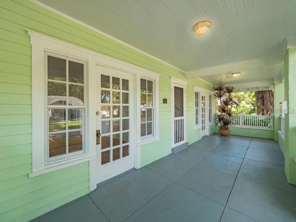 A covered porch with light green siding, gray flooring, and multiple white-framed glass doors — 510 N SUMMERLIN AVENUE, ORLANDO, FL