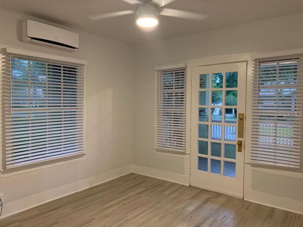 A room with light wood-look flooring, a ceiling fan, a mini-split unit, and a door — 510 N SUMMERLIN AVENUE, ORLANDO, FL