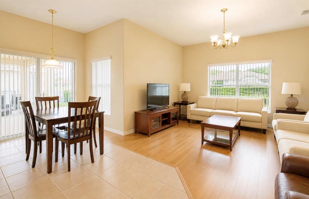 A combined living and dining area features tile and wood flooring, neutral walls, and furniture — 3578 VALLEYVIEW DRIVE, KISSIMMEE, FL