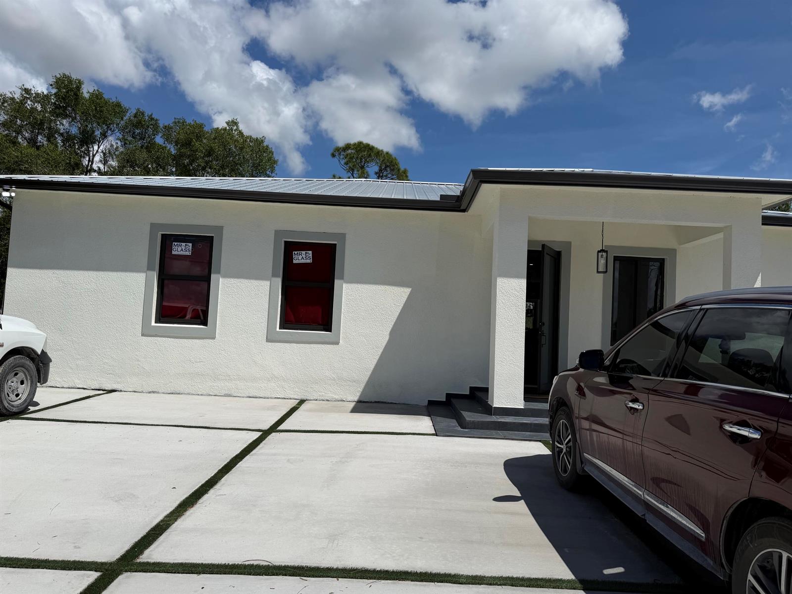 A white house with a metal roof and a concrete driveway with grass strips — 1101 Yeehaw Avenue, Clewiston FL 33440, CLEWISTON, FL