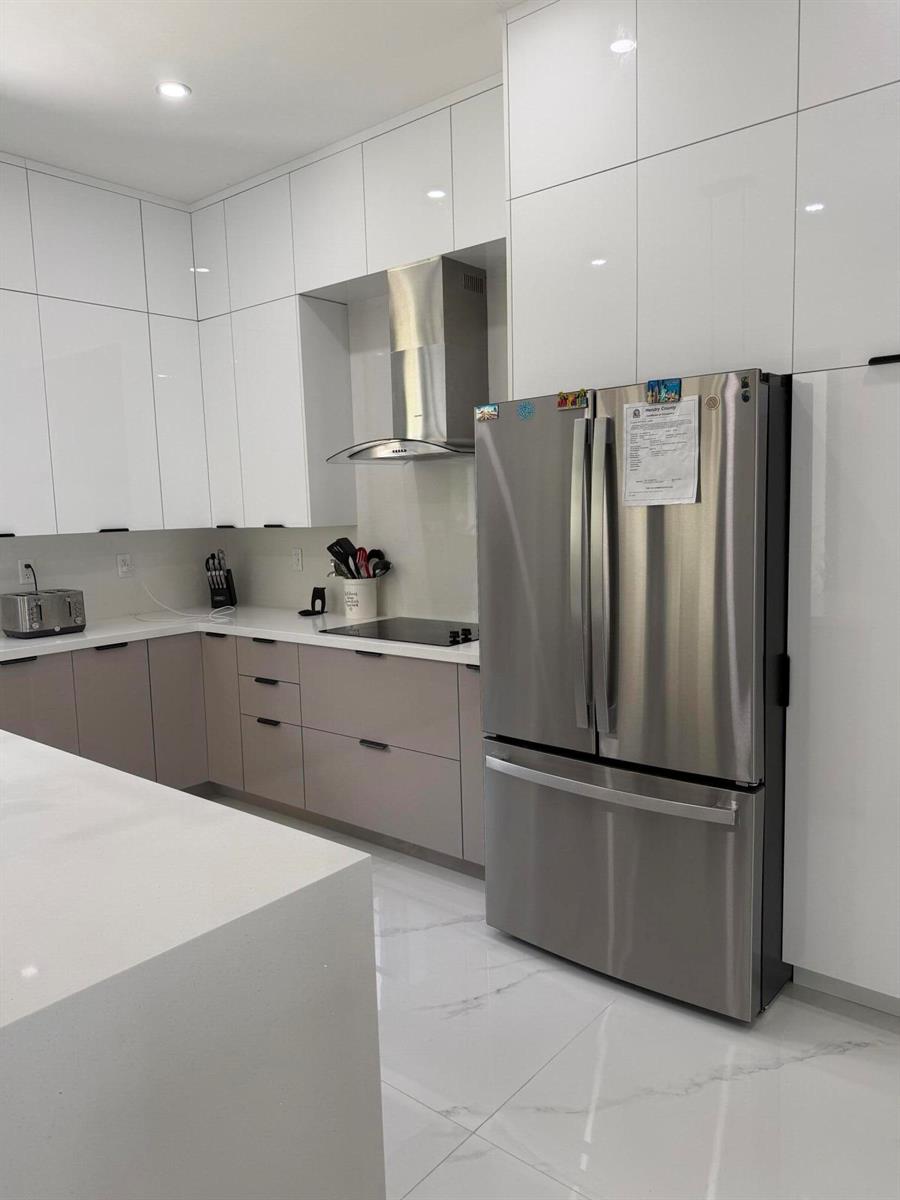 A modern kitchen features white upper cabinets, light gray lower cabinets, stainless steel appliances, and countertops — 1101 Yeehaw Avenue, Clewiston FL 33440, CLEWISTON, FL