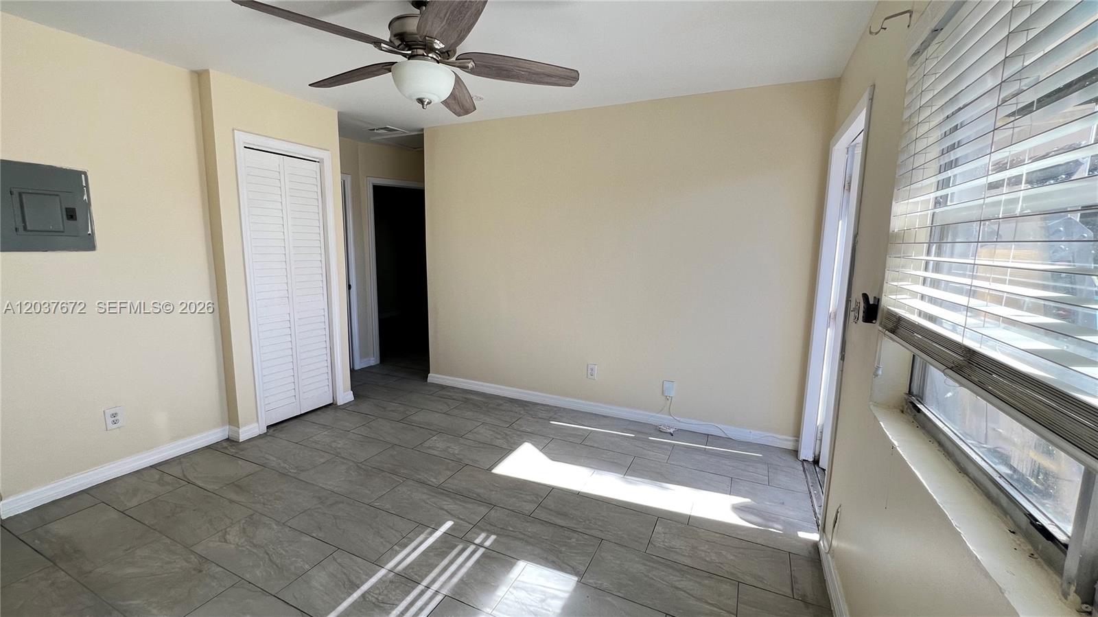 An empty room features light-colored walls, gray tile flooring, a ceiling fan, and a window — 706 SW 4th Ter # 4, Dania Beach FL 33004, DANIA BEACH, FL