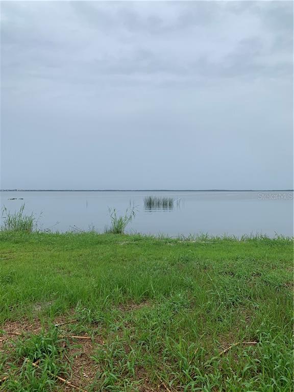 A grassy shoreline overlooks a calm lake under an overcast sky — 1061 ENTERPRISE OSTEEN ROAD, DELTONA, FL