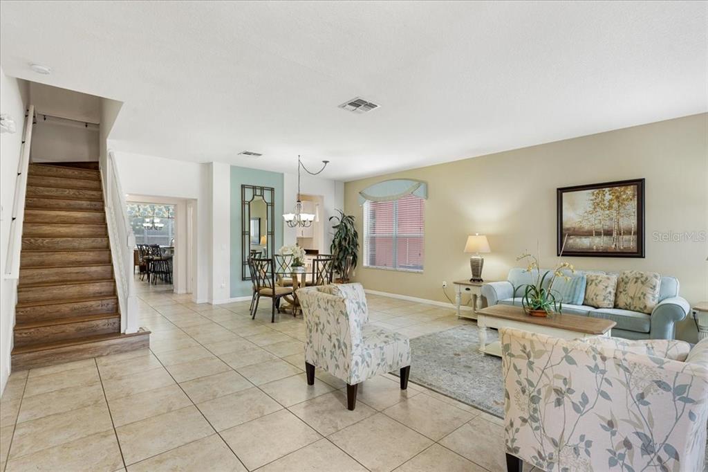 A living and dining area with tile floors, a wooden staircase, and light-colored walls — 211 LAS FUENTES DRIVE, KISSIMMEE, FL
