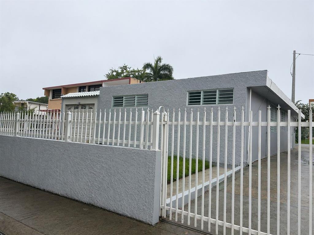 A gray, single-story house with a white metal fence and a concrete wall in front — 198 LOS PICACHOS, LA CUMBRE DEV., SAN JUAN, PR