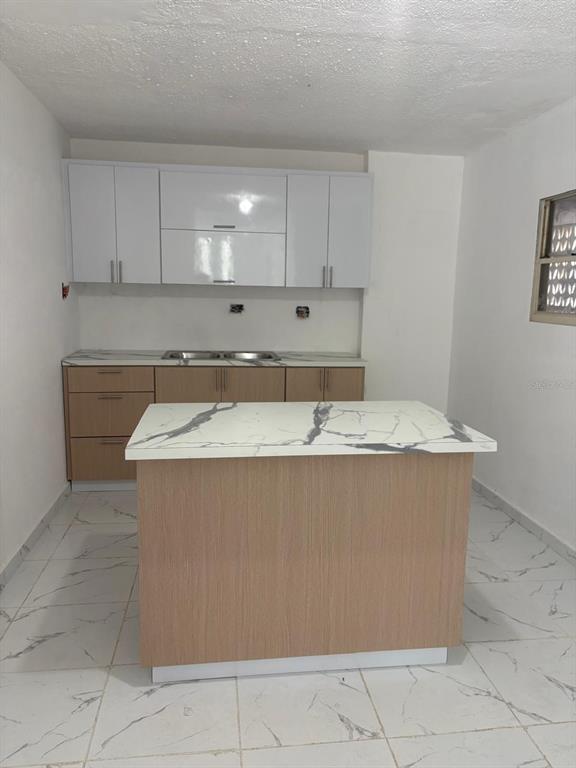 A kitchen features white upper cabinets, light wood lower cabinets, and a marble-patterned island — 198 LOS PICACHOS, LA CUMBRE DEV., SAN JUAN, PR